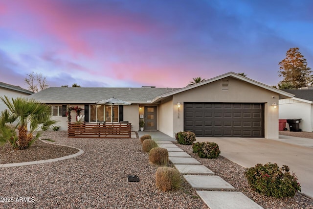 ranch-style home featuring stucco siding, an attached garage, and concrete driveway