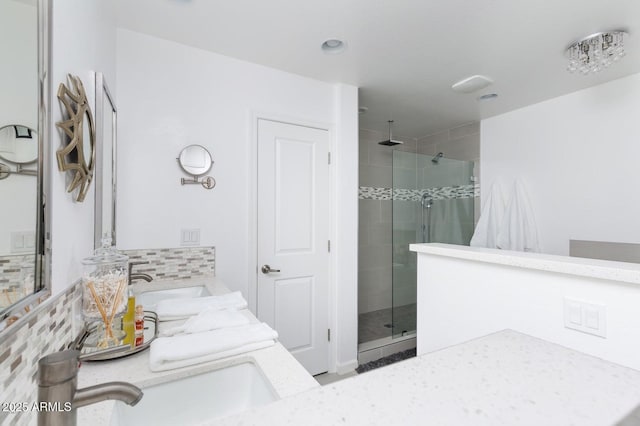 bathroom with double vanity, a stall shower, backsplash, and a sink