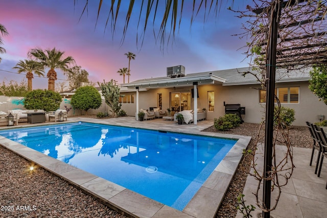 pool at dusk featuring fence, outdoor lounge area, a fenced in pool, central AC unit, and a patio area