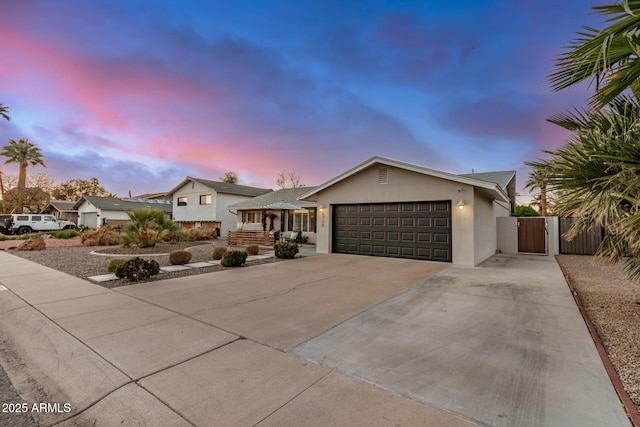 view of front of property with fence, stucco siding, a garage, driveway, and a gate