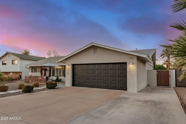 view of front of property with stucco siding, an attached garage, driveway, and a gate