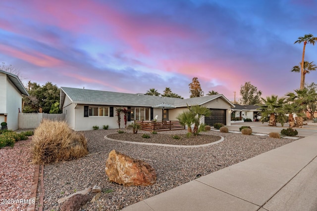 view of front of house with a garage, stucco siding, and fence