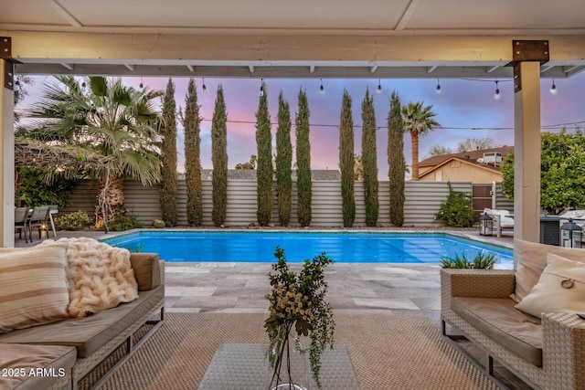 pool at dusk with an outdoor hangout area, a patio, and a fenced backyard