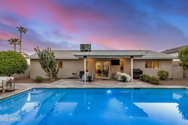 back of house featuring central AC, stucco siding, outdoor lounge area, a patio area, and an outdoor pool