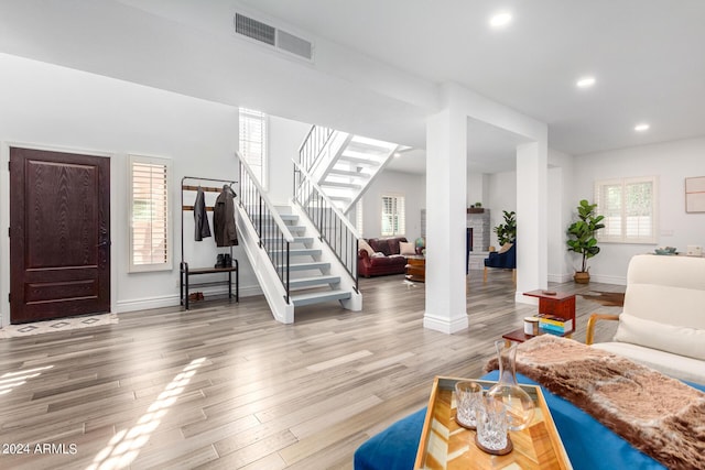 living area featuring recessed lighting, a fireplace, wood finished floors, visible vents, and stairway