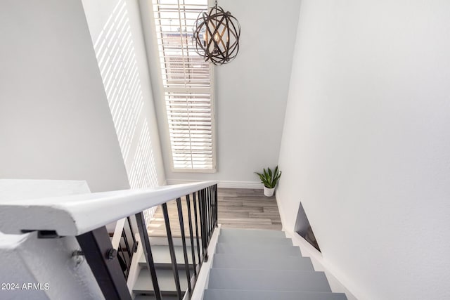 stairs featuring a chandelier, baseboards, and wood finished floors