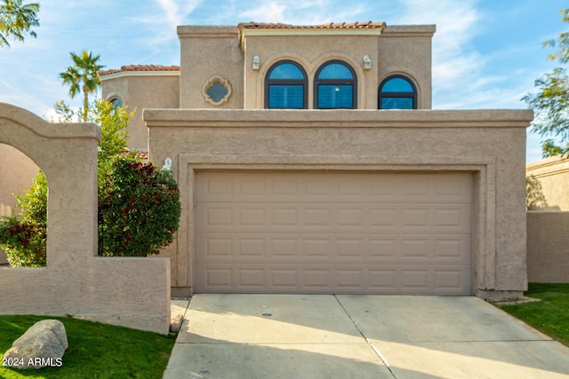 view of front of home with concrete driveway, a tiled roof, and stucco siding