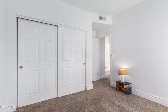 unfurnished bedroom with carpet floors, a closet, visible vents, and baseboards