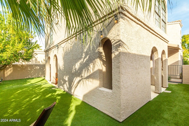 view of property exterior featuring fence, a lawn, and stucco siding