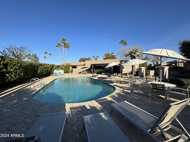 pool with a patio area and fence