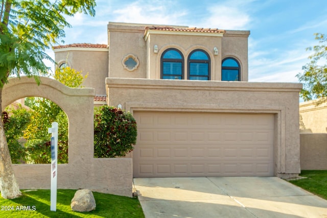 mediterranean / spanish home featuring concrete driveway, a tiled roof, an attached garage, and stucco siding