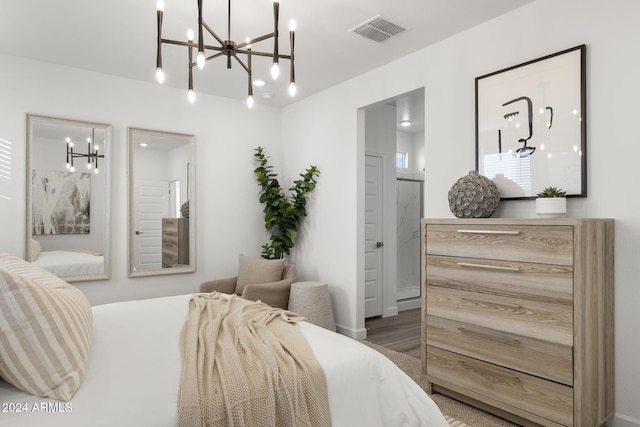 bedroom featuring a notable chandelier, dark wood-type flooring, and connected bathroom