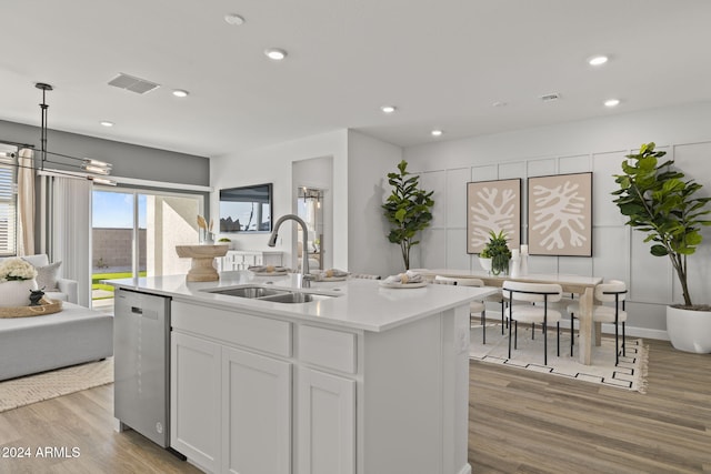 kitchen with sink, pendant lighting, a kitchen island with sink, white cabinets, and light wood-type flooring