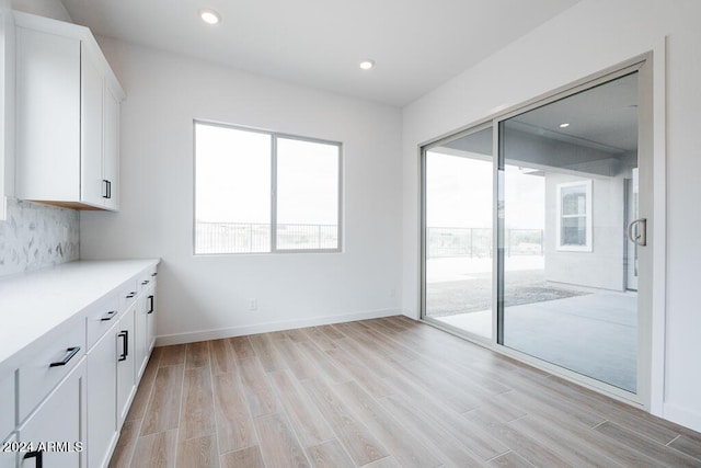 interior space featuring white cabinetry, decorative backsplash, and light hardwood / wood-style flooring