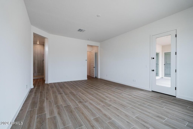 unfurnished bedroom featuring ensuite bathroom and light wood-type flooring