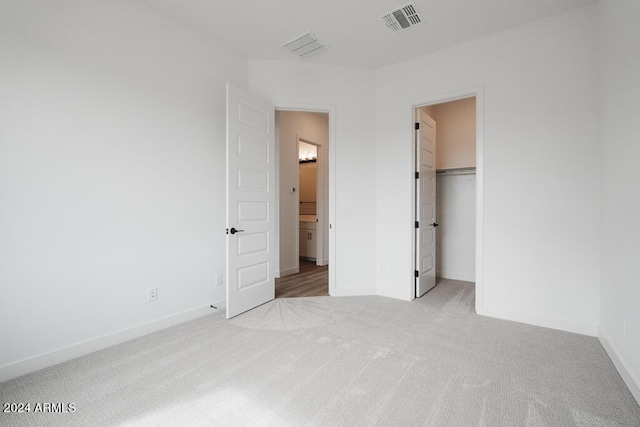 unfurnished bedroom with light carpet, a closet, and a spacious closet