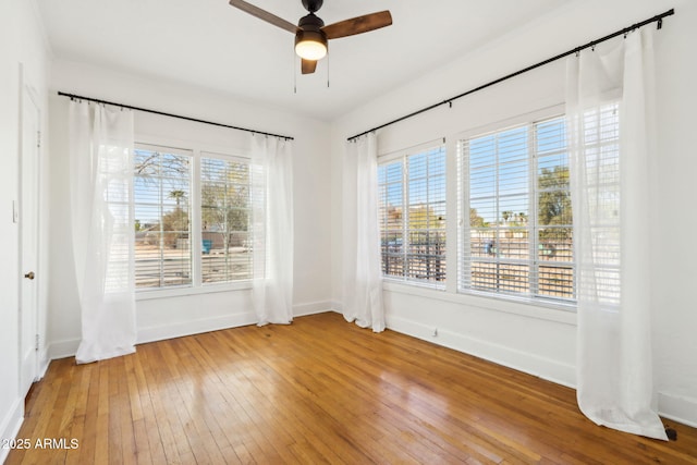 empty room with ceiling fan, wood-type flooring, and baseboards