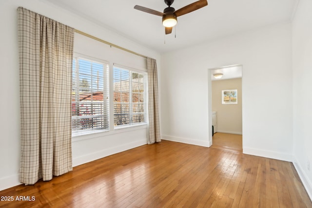 empty room featuring wood-type flooring, a ceiling fan, and baseboards