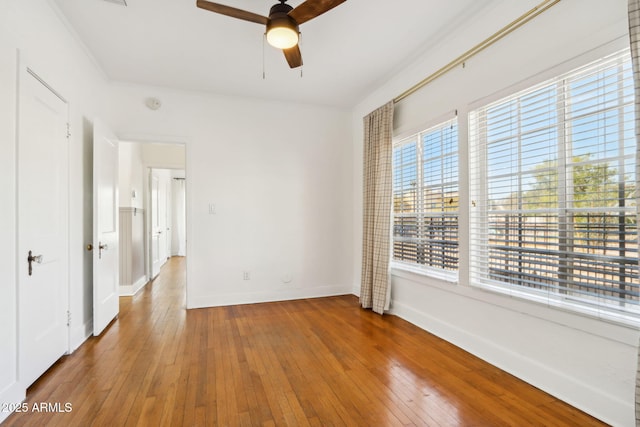 unfurnished room with a ceiling fan, wood-type flooring, and baseboards