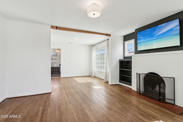 unfurnished living room with a fireplace, baseboards, and wood finished floors