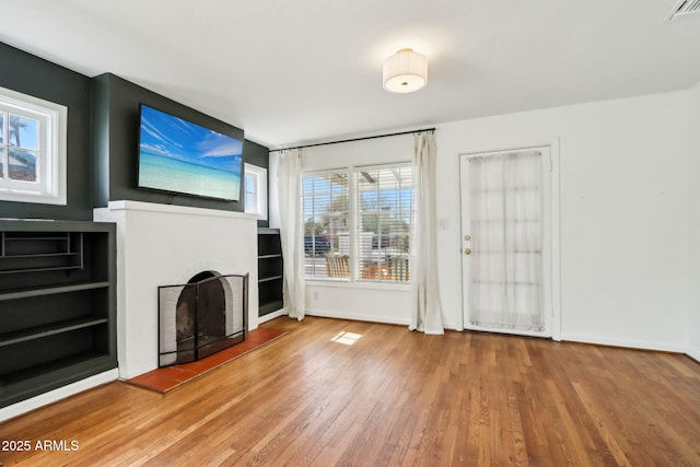 unfurnished living room with visible vents, a fireplace, baseboards, and hardwood / wood-style flooring