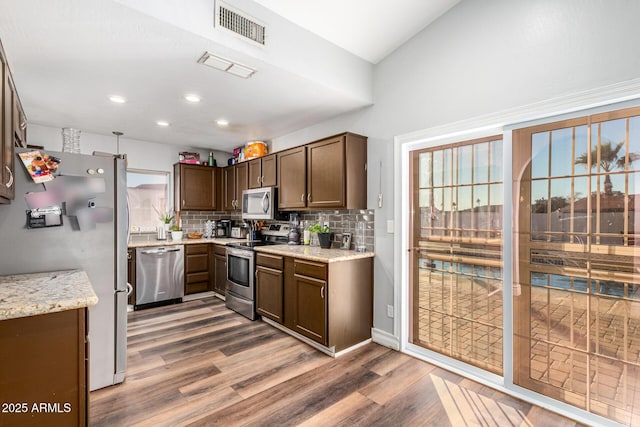 9169 W Ludlow Dr W, Peoria, AZ 85381 - kitchen featuring stainless steel appliances, decorative backsplash, visible vents, light stone countertops, and wood finished floors