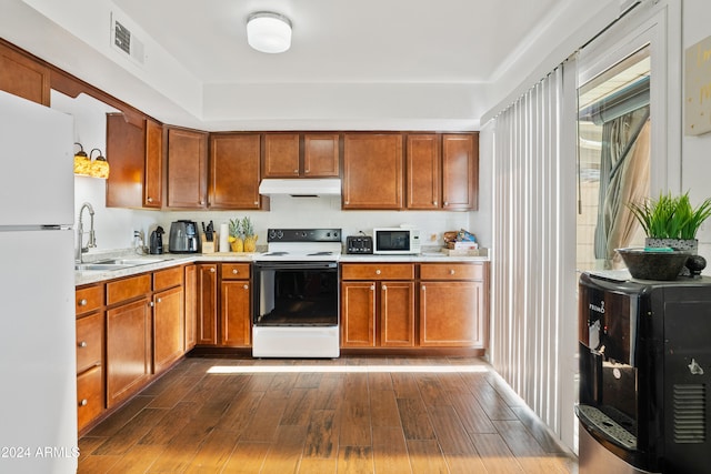 kitchen with dark hardwood / wood-style flooring, white appliances, and sink