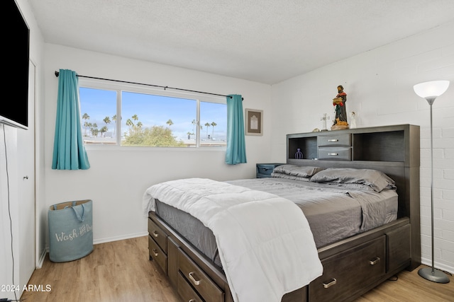 bedroom with light wood-type flooring and a textured ceiling