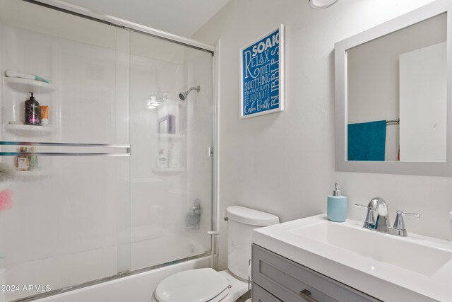 full bathroom with vanity, bath / shower combo with glass door, and toilet