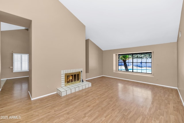 8666 E Cheryl Dr, Scottsdale, AZ 85258 - unfurnished living room featuring baseboards, wood finished floors, vaulted ceiling, and a tile fireplace
