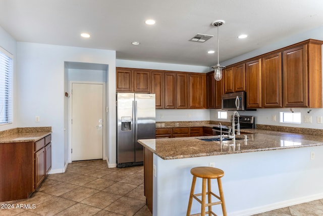 kitchen with stainless steel appliances, a healthy amount of sunlight, sink, decorative light fixtures, and dark stone countertops