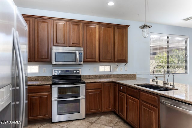 kitchen with appliances with stainless steel finishes, sink, light tile patterned floors, pendant lighting, and stone countertops