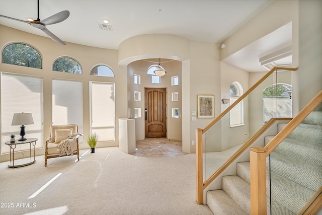 foyer entrance featuring carpet floors, a wealth of natural light, stairway, and visible vents