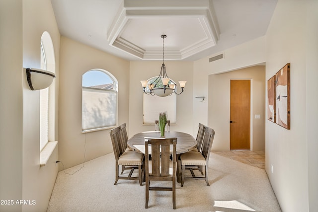 dining area with carpet floors, a tray ceiling, a chandelier, and visible vents