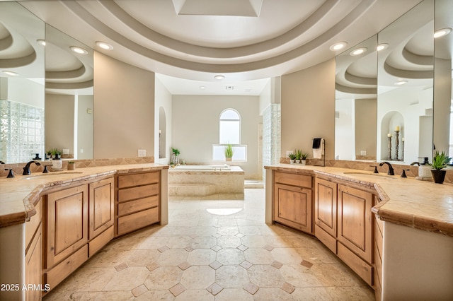 bathroom featuring a garden tub, two vanities, and a sink