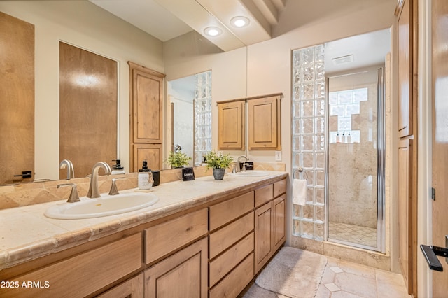 bathroom featuring tile patterned floors, a sink, a shower stall, and double vanity