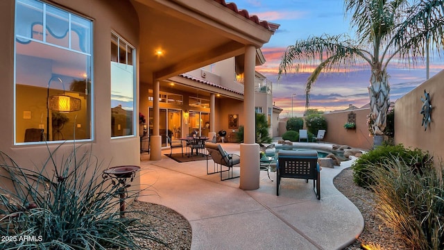 patio terrace at dusk featuring an in ground hot tub and fence