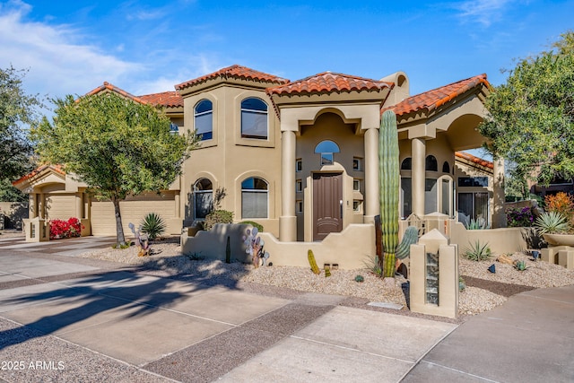 mediterranean / spanish home featuring a garage, driveway, a tiled roof, and stucco siding