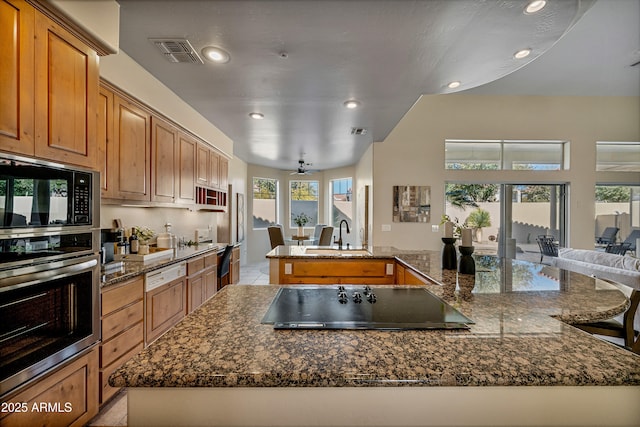 kitchen featuring visible vents, a large island, open floor plan, black appliances, and a sink