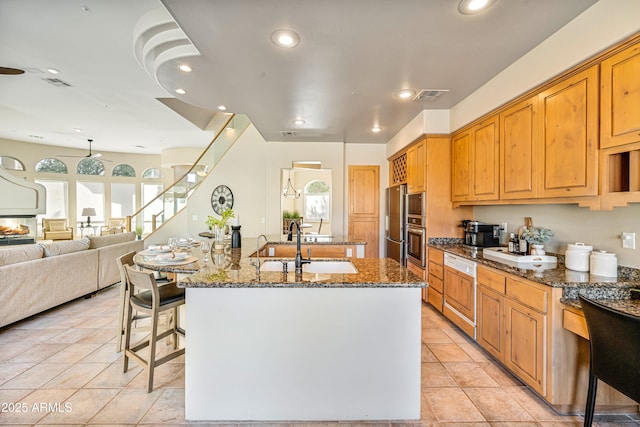 kitchen featuring an island with sink, visible vents, dark stone counters, and recessed lighting