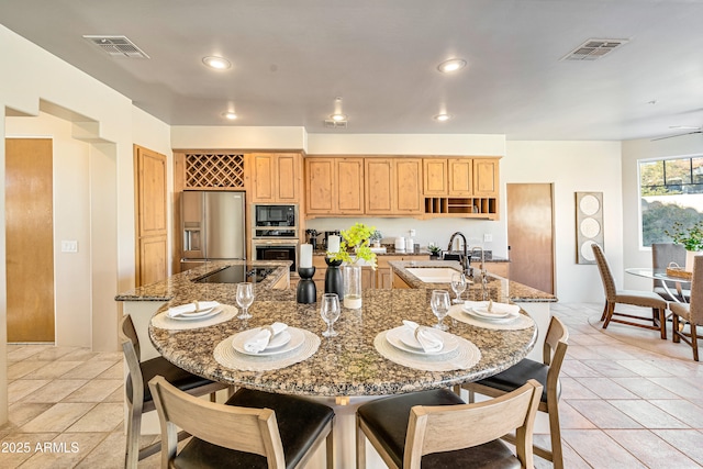 kitchen featuring black appliances, visible vents, a kitchen breakfast bar, and a sink