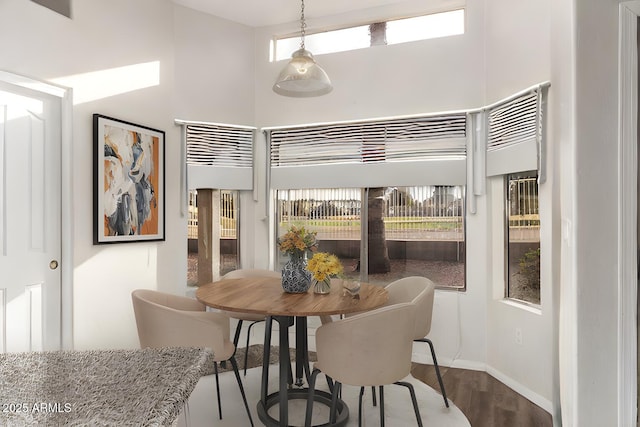 dining space with hardwood / wood-style floors and a high ceiling