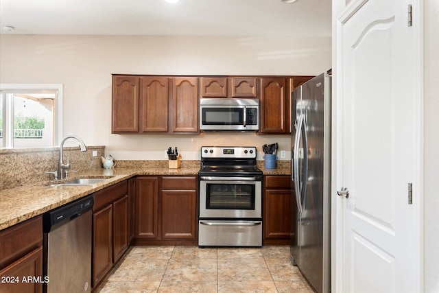 kitchen featuring light stone counters, sink, and appliances with stainless steel finishes