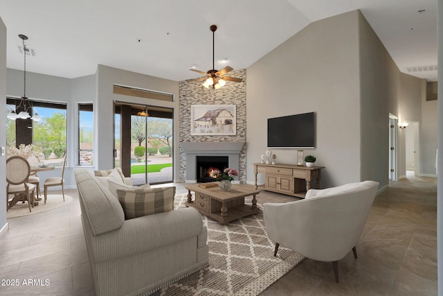 living area with high vaulted ceiling, ceiling fan with notable chandelier, a large fireplace, baseboards, and visible vents