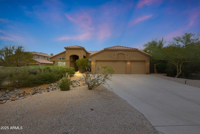 mediterranean / spanish home with concrete driveway, an attached garage, a tile roof, and stucco siding