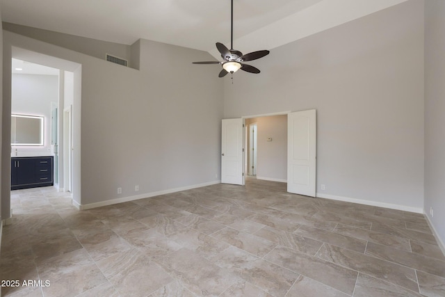 unfurnished room featuring baseboards, visible vents, a high ceiling, and ceiling fan