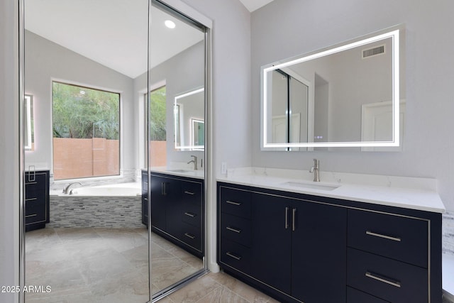 full bathroom featuring a garden tub, vaulted ceiling, a sink, two vanities, and visible vents