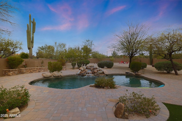 pool at dusk with a fenced backyard, a fenced in pool, and a patio