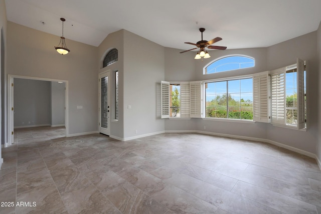 interior space featuring a ceiling fan, baseboards, and high vaulted ceiling