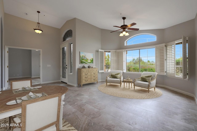 interior space with baseboards, a ceiling fan, and high vaulted ceiling